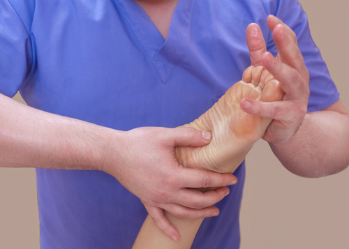 Podiatre qui pratique la thérapie manuelle sur le pied d'un patient au niveau de l'arche plantaire