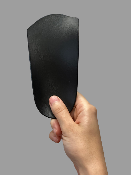 Orthèse plantaire en plastique noir tenue dans la main